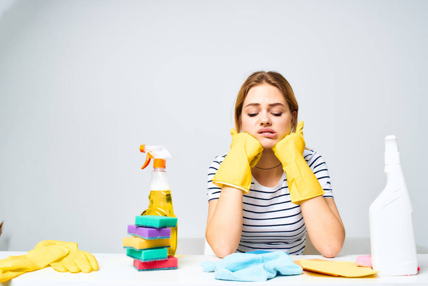 cleaning lady sitting at the table washing supplies work pallets light background - Foto, Bild