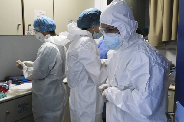 Een medisch medewerker kleedt zich in persoonlijke beschermingsmiddelen (PPE) voordat hij op 5 november 2020 COVID-19 patiënten in het ziekenhuis van Athene in Griekenland assisteert.. - Foto, afbeelding