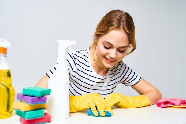 Cheerful cleaning lady wipes the table with detergents cleaning tools - Photo, Image