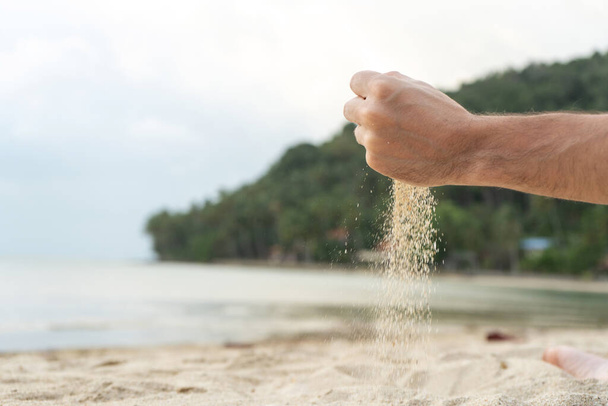 Play with sand on the beach. Sand is poured from the hands, against the backdrop of a tropical island - Foto, immagini