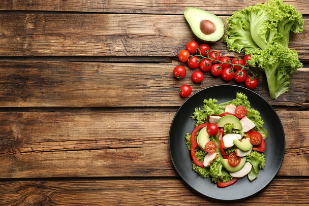 Delicious fresh chicken salad and vegetables on wooden table, flat lay. Space for text - Foto, afbeelding