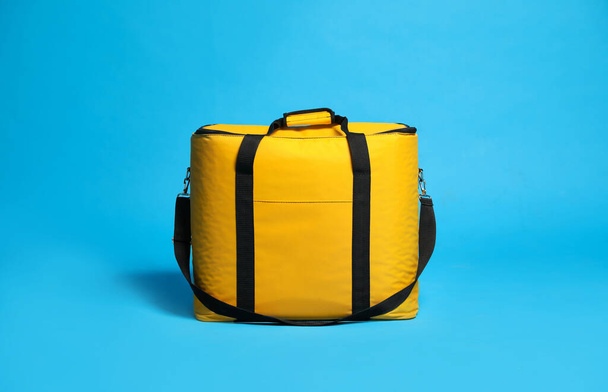 Modern yellow thermo bag on light blue background - Foto, afbeelding
