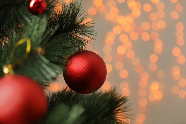 Red holiday bauble hanging on Christmas tree against blurred festive lights, closeup. Space for text - Foto, Bild