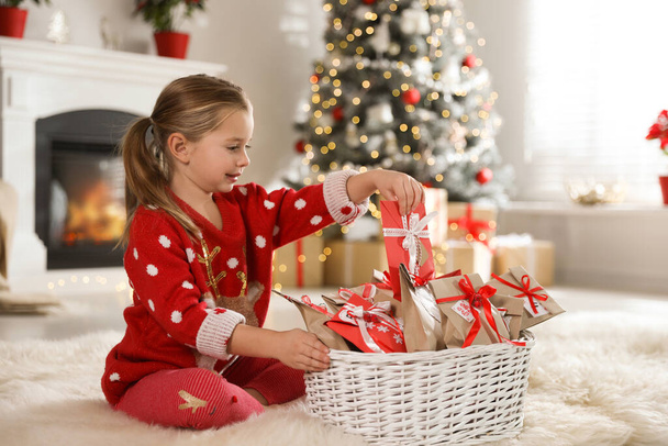 Cute little girl taking gift from Christmas advent calendar at home - Zdjęcie, obraz