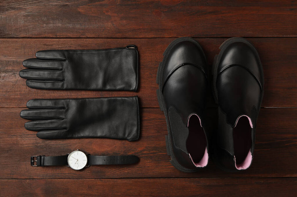 Stylish black leather gloves, pair of shoes and wristwatch on wooden table, flat lay - Foto, Imagen
