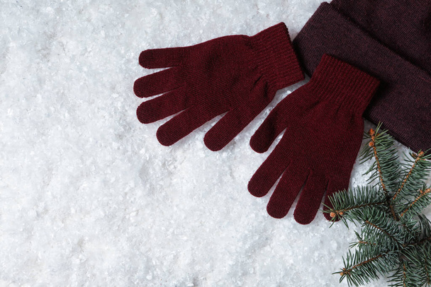 Stylish woolen gloves, hat and fir branches on artificial snow, flat lay. Space for text - Foto, immagini