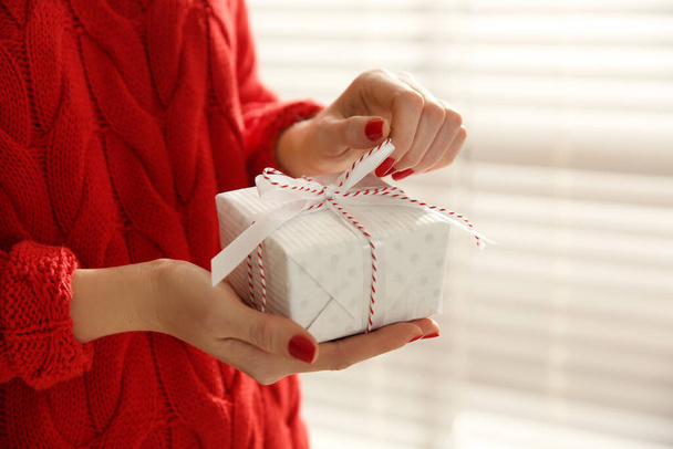 Woman holding white Christmas gift box indoors, closeup - Fotografie, Obrázek