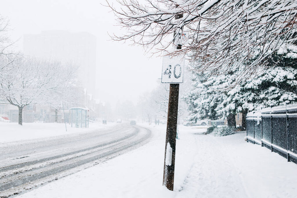 Tienopeuskyltti lumen alla. Rankka lumisade ja lumimyrsky Torontossa, Ontariossa, Kanadassa. Lumimyrsky ja huonot sääolosuhteet. Kuljettajien huono näkyvyys ja kausiluonteinen vaara. - Valokuva, kuva