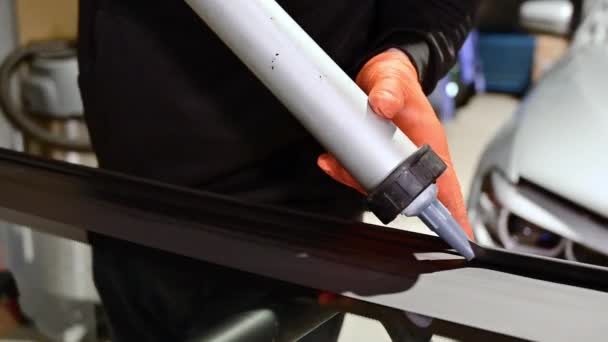 Glazier aanbrengen rubber afdichting op voorruit in garage, close-up. - Video