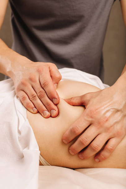 Caucasian young woman receiving anti-cellulite massage at spa center. The therapist warms up the muscles for the oil massage - Valokuva, kuva