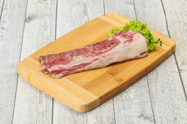 Ωμό μπέικον βοδινό πάνω από ξύλινη σανίδα σερβίρεται σαλάτα και θυμάρι - Φωτογραφία, εικόνα