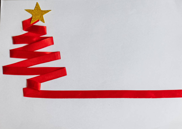 Czerwone choinki wykonane z czerwonej wstążki i złotej gwiazdy i dzwonków Bożego Narodzenia na białym tle. - Zdjęcie, obraz