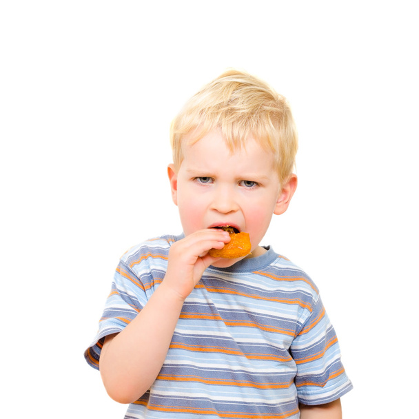 Cute little boy eating delicious cookie isolated on white - Photo, Image