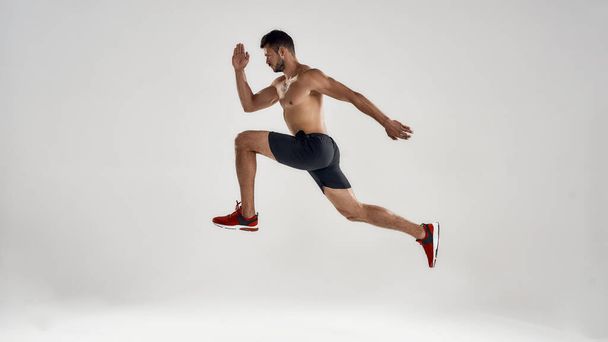 Young handsome caucasian male runner jumping high - Φωτογραφία, εικόνα