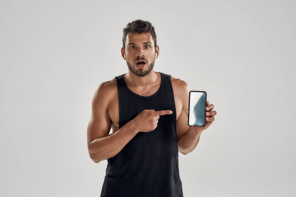 Young muscular caucasian athlete pointing into smartphone screen - Foto, Imagem