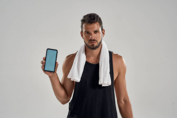 Young muscular caucasian man after training holding smartphone - Zdjęcie, obraz