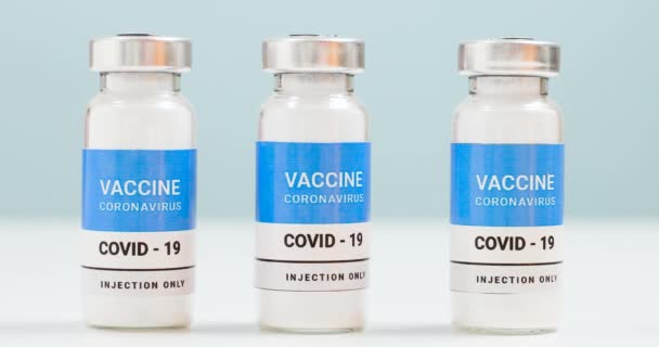 Koronowirus, szczepienie przeciw wiremii 19 populacji. Fiolki i strzykawka ze szczepionką SARS-CoV-2 na białym stole laboratoryjnym z przestrzenią do kopiowania. Koncepcja leczenia opieki zdrowotnej - Materiał filmowy, wideo