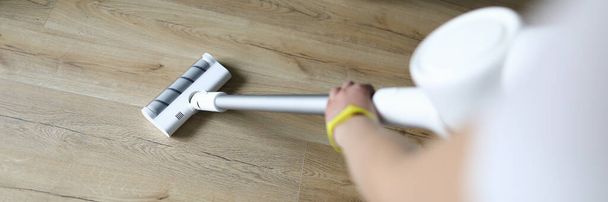 Female hand vacuums floor covering in an apartment - Photo, Image