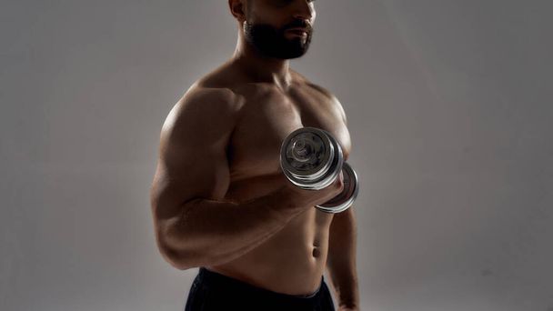 Blacked figure of young muscular athlete lifting dumbbell - Foto, Imagem