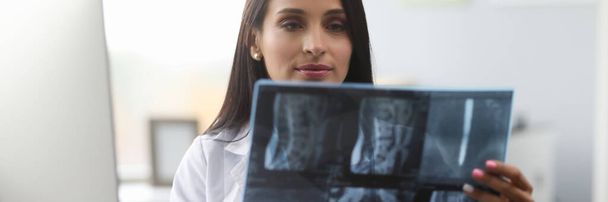 Röntgenképet vizsgáló, koncentrált, fiatal egészségügyi dolgozó - Fotó, kép