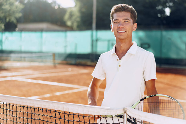 Young mixed race man tennis player with racket standing on tennis court - Foto, Bild