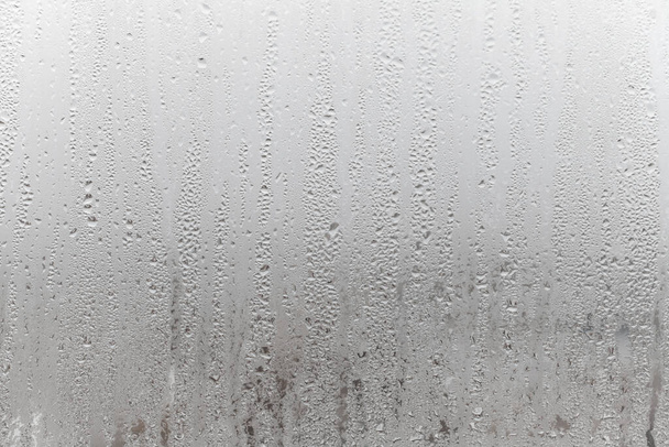 Закрыть на туманное стекло с каплями воды, стекающими вниз. Капельная конденсация, капли воды Фон капли дождя Конденсация текстура - Фото, изображение
