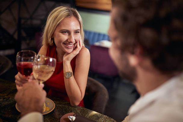 beautiful caucasian blonde toasting with a man, with in love look in her eyes - 写真・画像