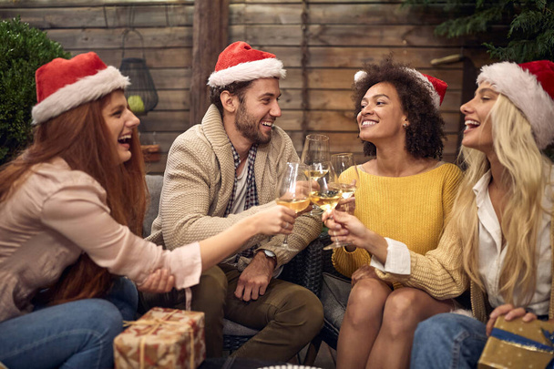 two couples, strait and lesbian, celebrating new year together, wearing santa hats, toasting - Фото, изображение