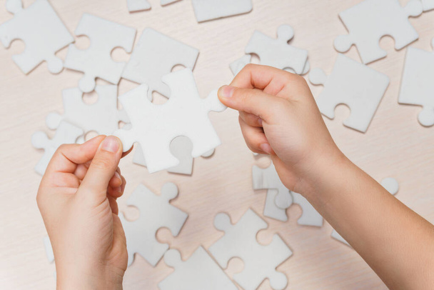 a child's hand makes the last missing piece of the puzzle on the table. strategy business concept - Фото, зображення
