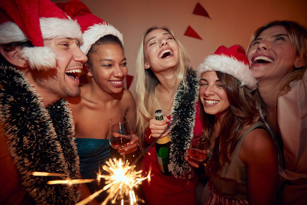 group of people at new year party, drinking alcohol, wearing santa hats - Photo, image