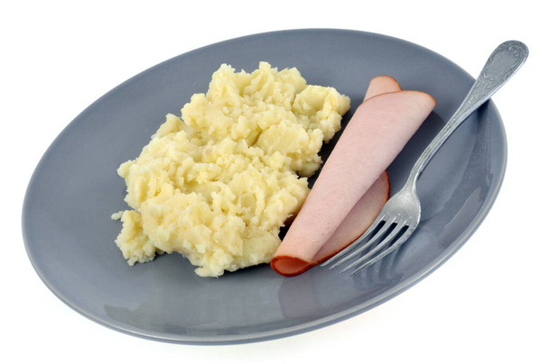 Plato de puré de papas con una rebanada de jamón y un primer plano tenedor sobre fondo blanco  - Foto, imagen