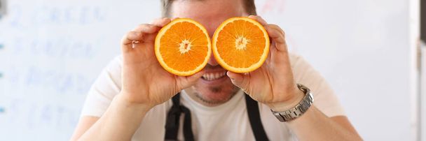Закрыть игривого повара, позирующего с апельсинами - Фото, изображение