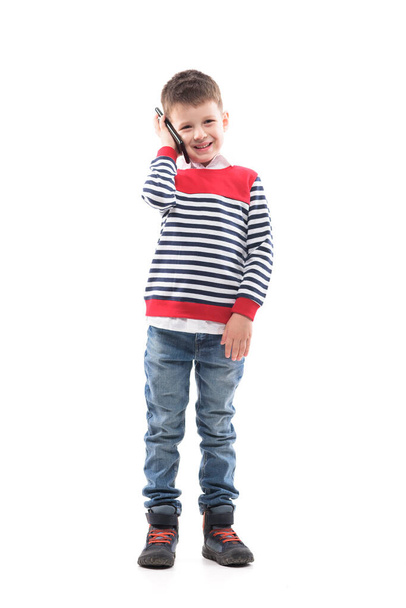 Happy cheerful stylish little kid talking on the cell phone looking at camera. Full body portrait isolated on white background.  - Φωτογραφία, εικόνα