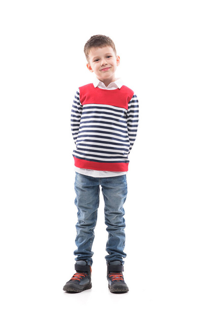 Mignon élégant charmant petit garçon cool en pull posant avec les mains derrière le dos. Portrait intégral isolé sur fond blanc.  - Photo, image