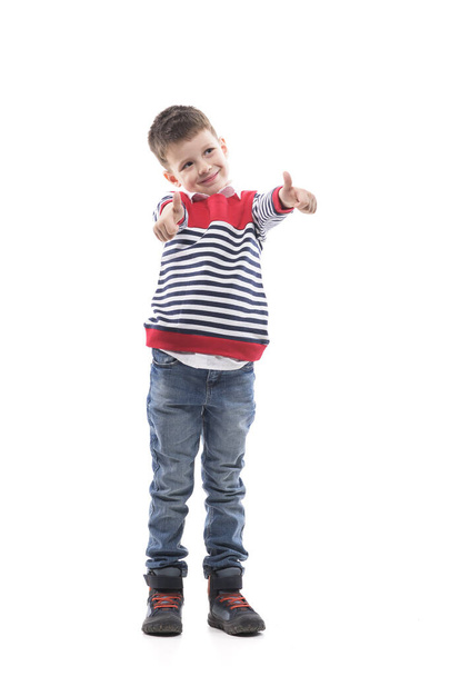 Heureux petit enfant excité montrant pouces vers le haut gestes détournant les yeux. Portrait intégral isolé sur fond blanc.  - Photo, image