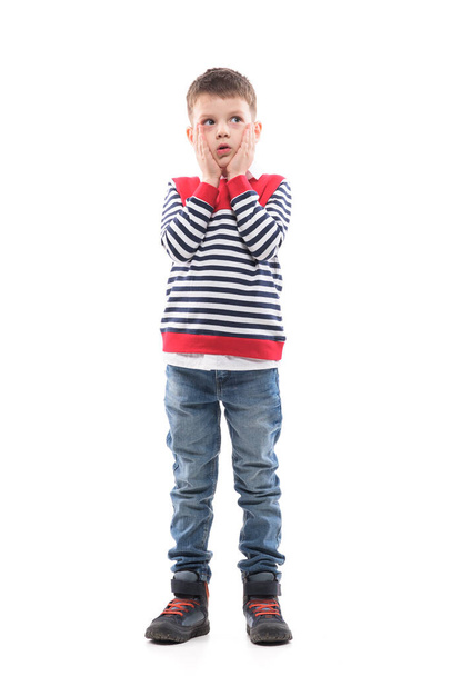 Thinking young serious cute little boy looking up confused touching cheeks. Full body portrait isolated on white background.  - Foto, Imagen
