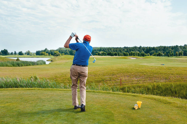 Mannelijke golfspeler op professionele golfbaan. Golfer met golfclub neemt een schot - Foto, afbeelding