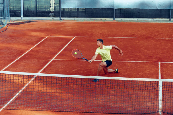 Young handsome man playing tennis on the tennis court - Φωτογραφία, εικόνα