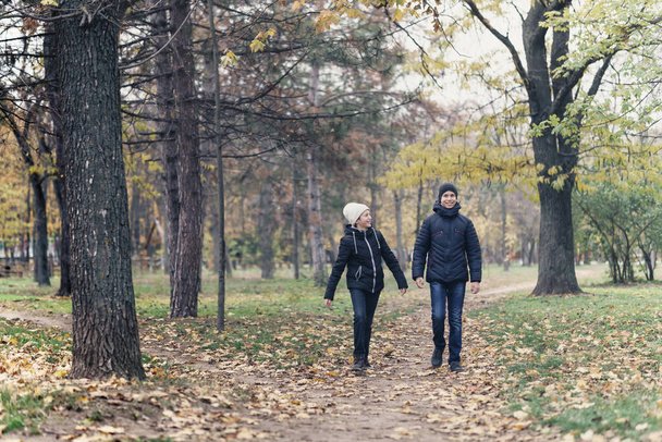 teen girl and boy walking through the park and enjoys autumn, beautiful nature with yellow leaves - Φωτογραφία, εικόνα