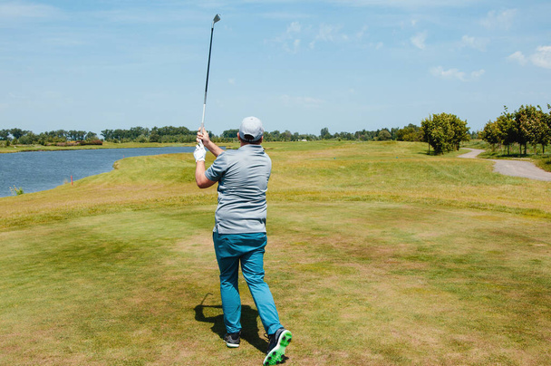 Male golf player on professional golf course. Golfer with golf club taking a shot - Fotografie, Obrázek