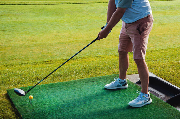 Profesyonel golfçü topu deliğe sokuyor. Güneşli bir günde arka planda oyuncuyla deliğin kenarında golf topu. - Fotoğraf, Görsel