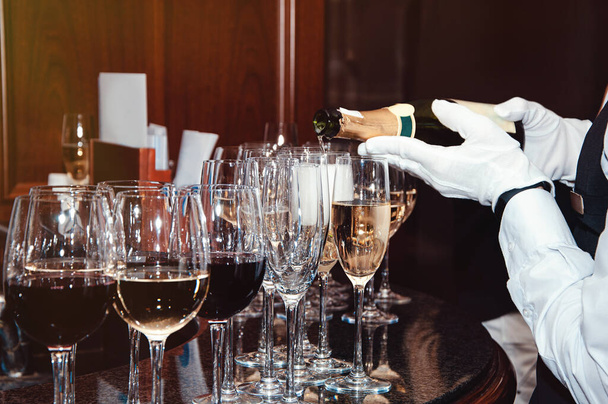 The bartender pours champagne into the empty glasses from the bottle - Fotoğraf, Görsel