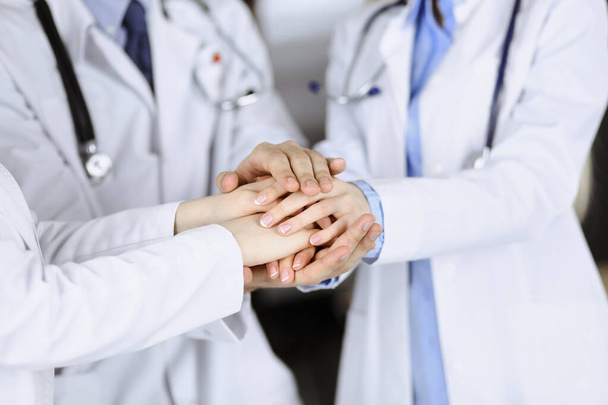 Group of modern doctors joining hands as a circle and ready to help patients. Teamwork in medicine during Coronavirus pandemic. Covid 2019 - Photo, image
