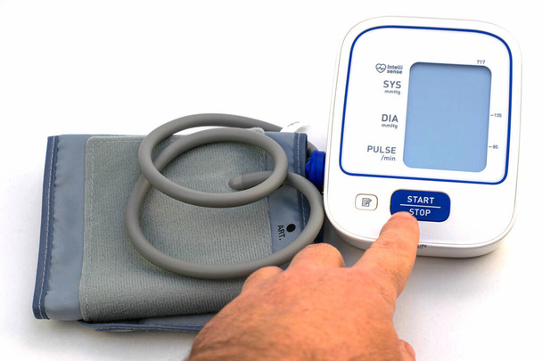 血圧計を測定する装置は白い背景にあります人は指でスタートボタンを押す - 写真・画像