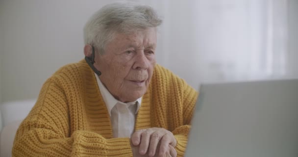 Vanha nainen puhuu tyttärentyttärensä kanssa videopuhelussa kannettavalla tietokoneella.Videoneuvottelu lääkärin kanssa - Materiaali, video