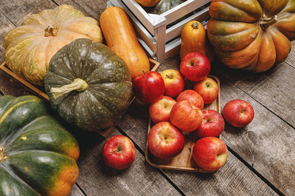Pumpkins and red apples on wooden background - Foto, Imagen