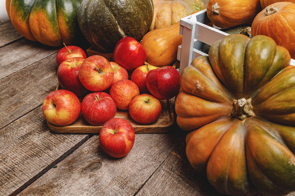 Pumpkins and red apples on wooden background - Фото, изображение