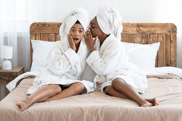 Pretty african american women sharing secrets, home interior - Фото, изображение