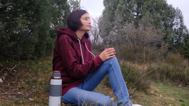 женщина путешественник пьет термос чай на фоне природы - Кадры, видео