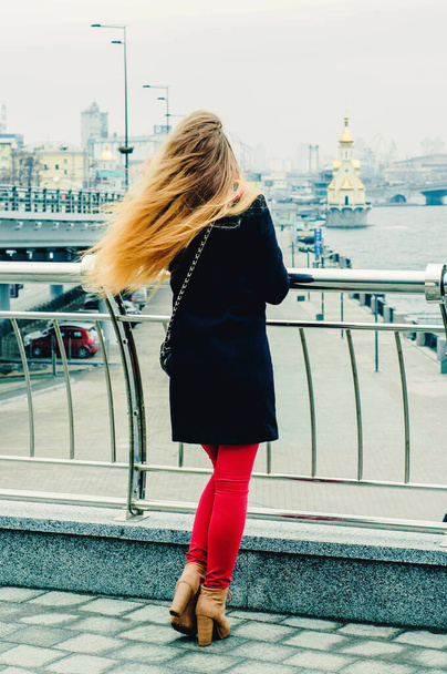 Young beautiful blonde stands on the bridge and sad. Winter portrait. - Foto, immagini